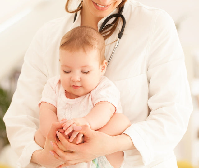 Pediatrician in a white coat gently holding a calm baby